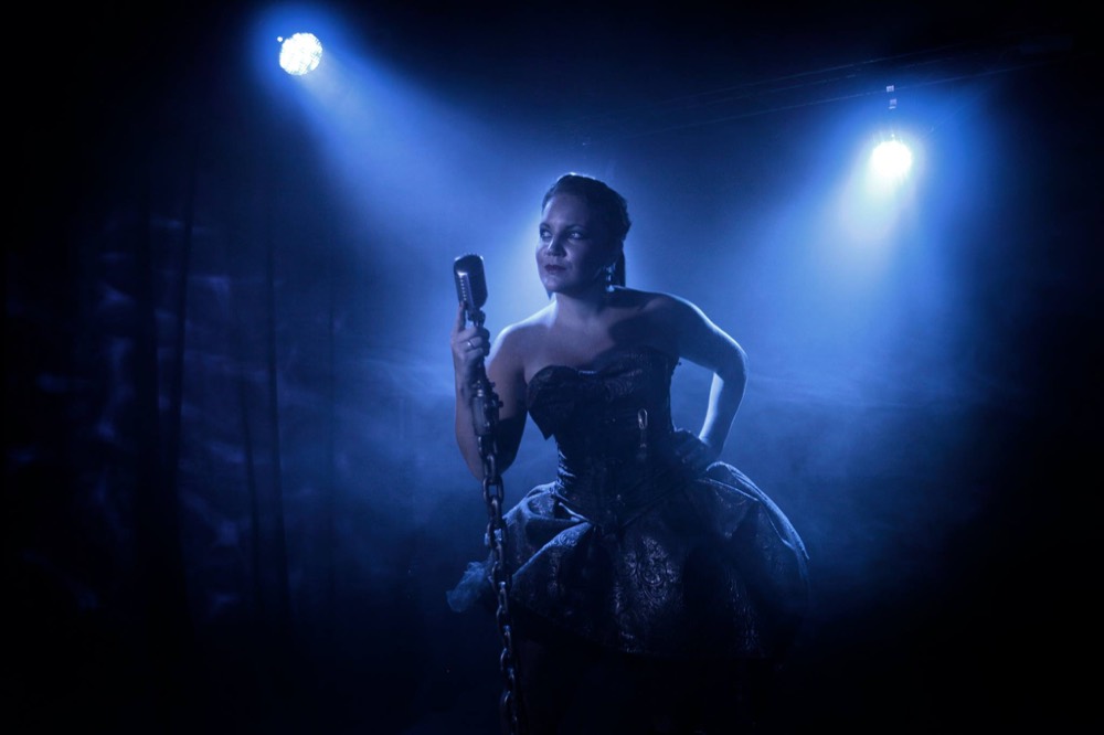 Alarna singing under a blue spotlight with a vintage microphone